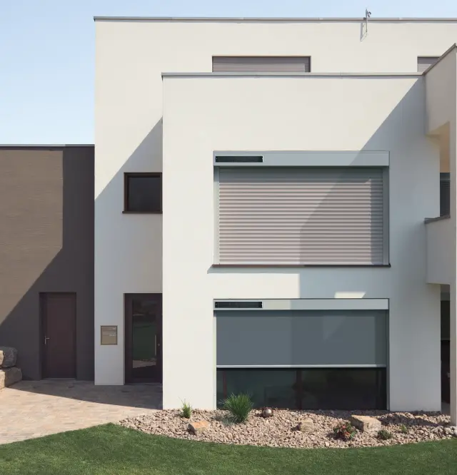 Modernes kubisches Einfamilienhaus mit solarbetriebenen Rollladen und Markisen anden Fenstern