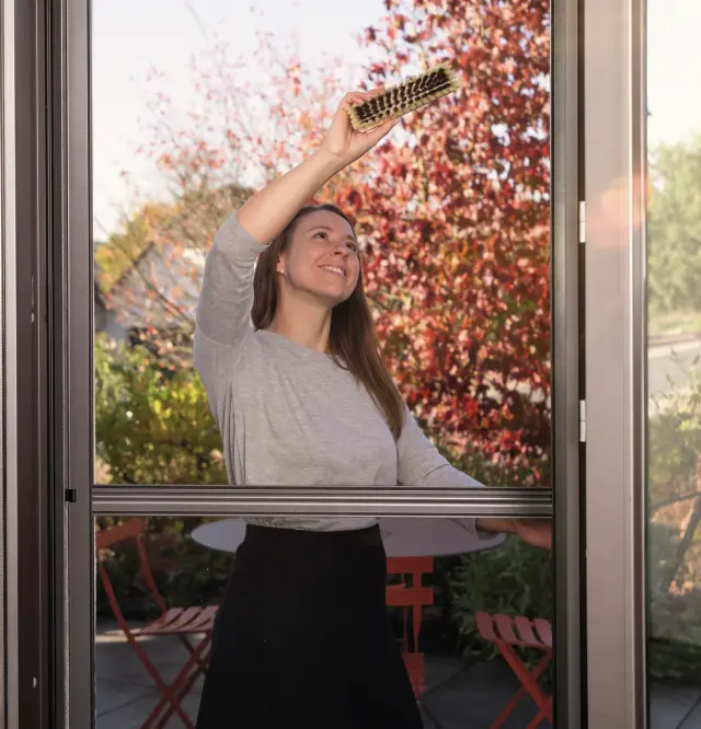 Vrouw reinigt hor op het terras met herfstbladeren