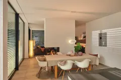 Pièce d'habitation avec une grande fenêtre munie de brise-soleil orientables dans une ambiance lumineuse conviviale