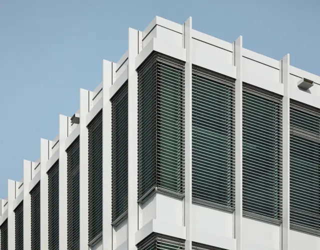 Blick auf Ecke einer weißen Fassade mit Raffstore außen