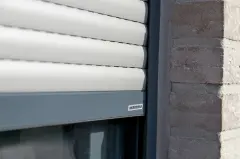 Detailaufnahme eines Rolladenprofils am Fensterrahmen mit WAREMA-Logo auf der Führungsschiene