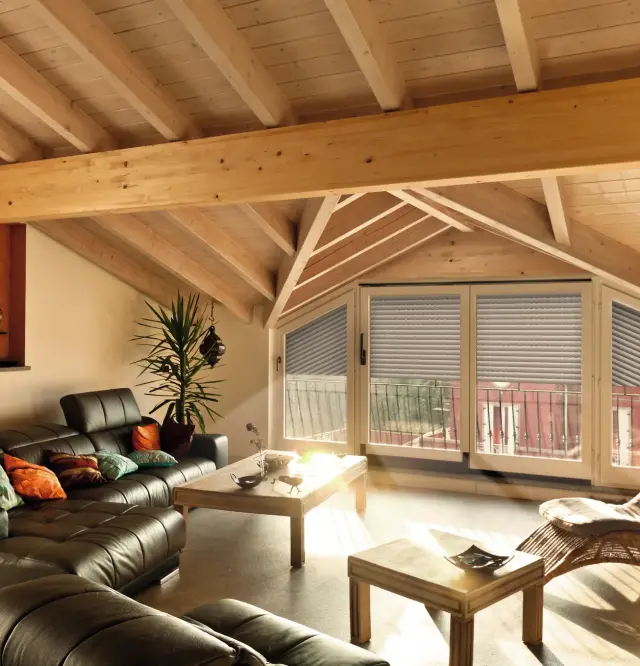 Binnenaanzicht van een woonruimte op zolder met een schuin geplaatste rolluik op het topgevelraam.