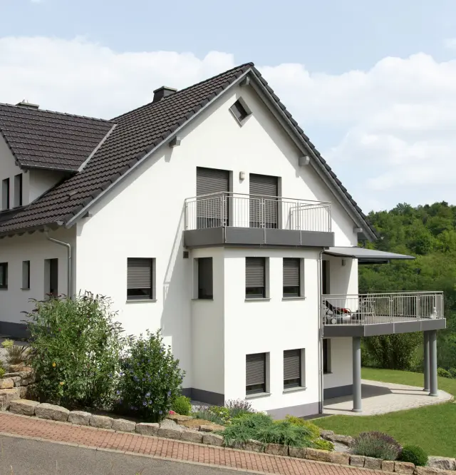 Sonnenschutzrollos an modernen Fenstern eines Einfamilienhauses – effektiver Hitze- und Sichtschutz im Sommer