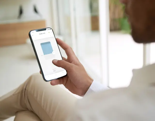Bild einer Frau am Handy bei der Bedienung einer Smart-Home-Lösungen von Anwis
